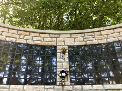 photo of columbarium wall, a stone wall with names inscribed on little black plaques
